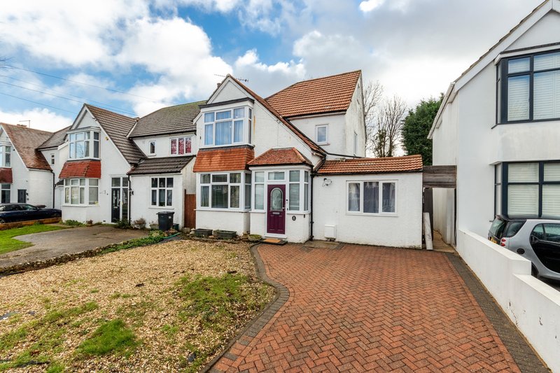 White detached house with brick driveway, front garden and parked car