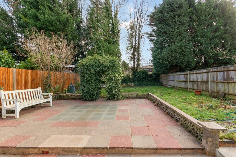 Patio garden with brick paving, white bench, wooden fences and landscaping