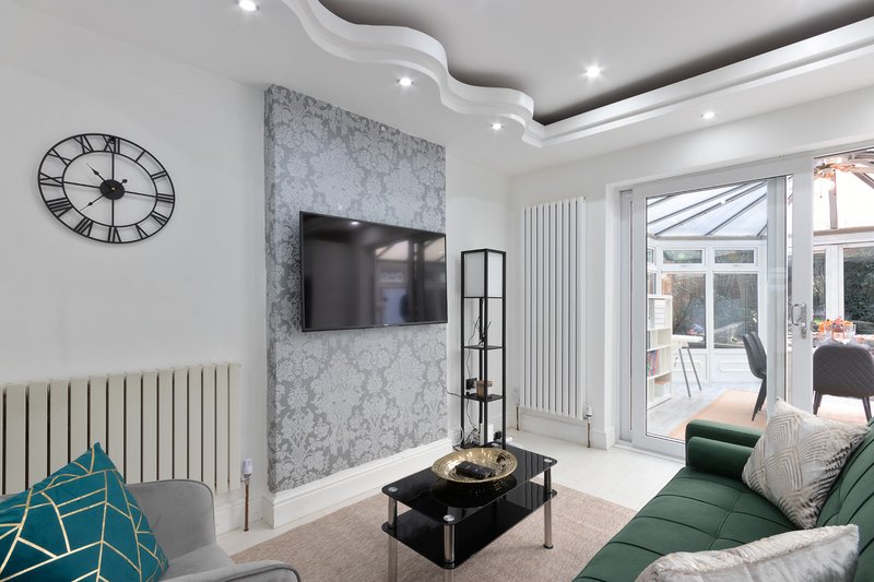 Modern living room with TV on marble feature wall, green sofa, and patio doors