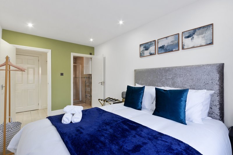 Modern bedroom with double bed, navy bedding, grey headboard and lime green accent wall