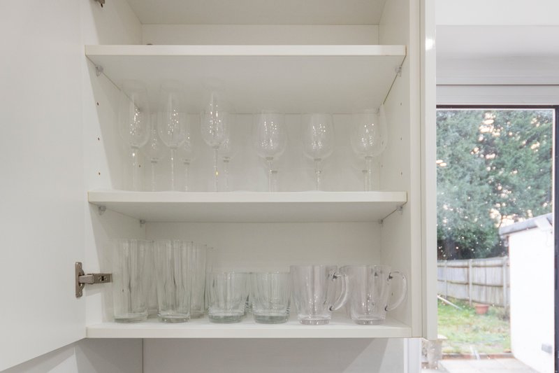 White shelving cabinet with crystal glasses, drinking glasses and pitcher displayed inside