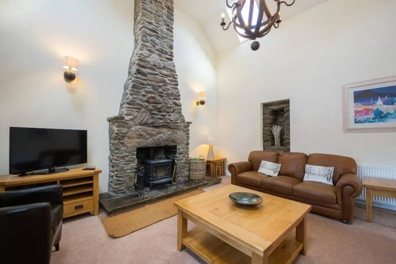 Living room with stone fireplace, brown sofa, wooden coffee table and TV