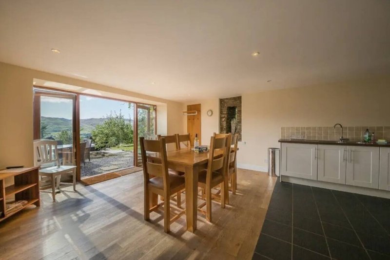 Open-plan dining and kitchen area with wooden table, chairs, and view to garden