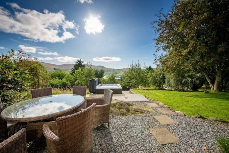 Outdoor garden area with hot tub, seating, manicured lawn and mountain views