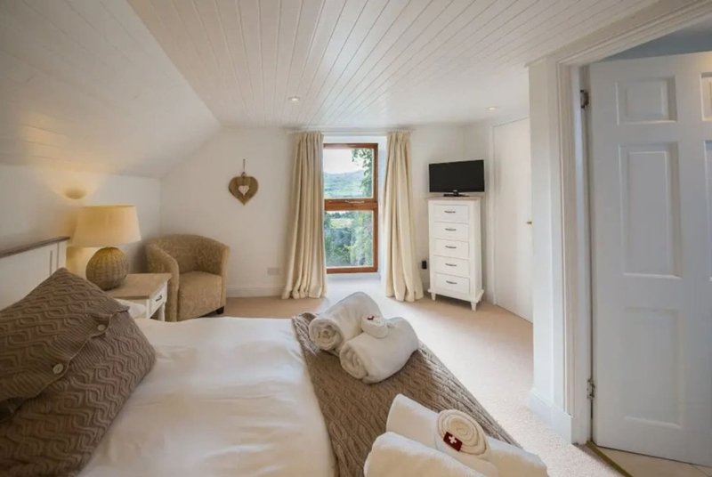 Bright bedroom with twin beds, white walls, sloped ceiling and countryside views