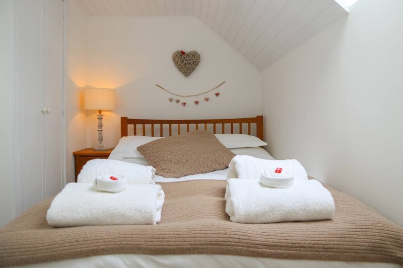 Cozy bedroom with wooden bed, white pillows, folded towels and heart decoration