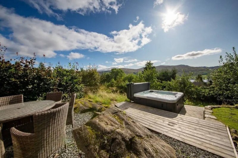 Elevated garden deck with outdoor furniture, hot tub and mountain views