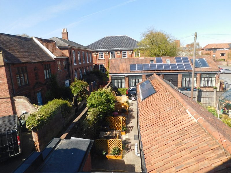 Aerial view of brick residential property with solar panels, courtyard garden and surrounding buildings