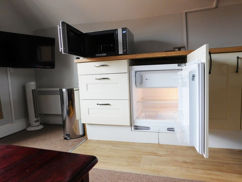 Kitchenette with white cabinetry, microwave, open mini-fridge, and wooden countertop