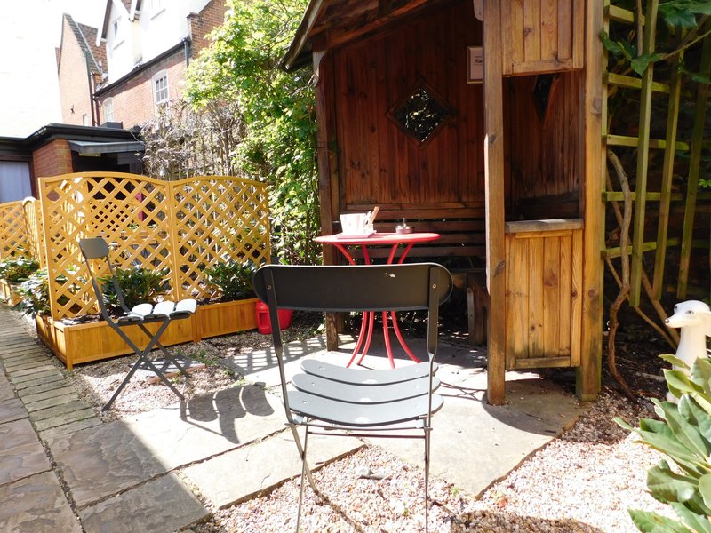 Garden seating area with wooden pergola, table, chairs and potted plants
