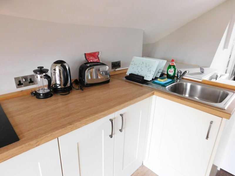 Modern kitchen with white cabinetry, wooden countertop, and various small appliances and items