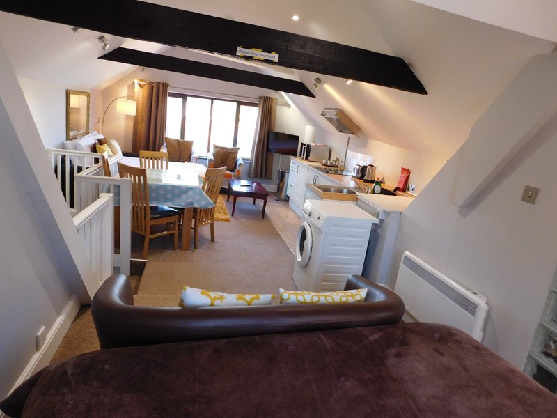 Open-plan attic bedroom with kitchen area, dining table, and en-suite bathroom visible