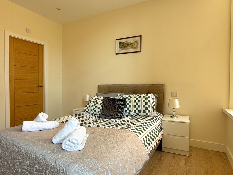 Bedroom with double bed, patterned bedding, wooden door, and bedside lamp