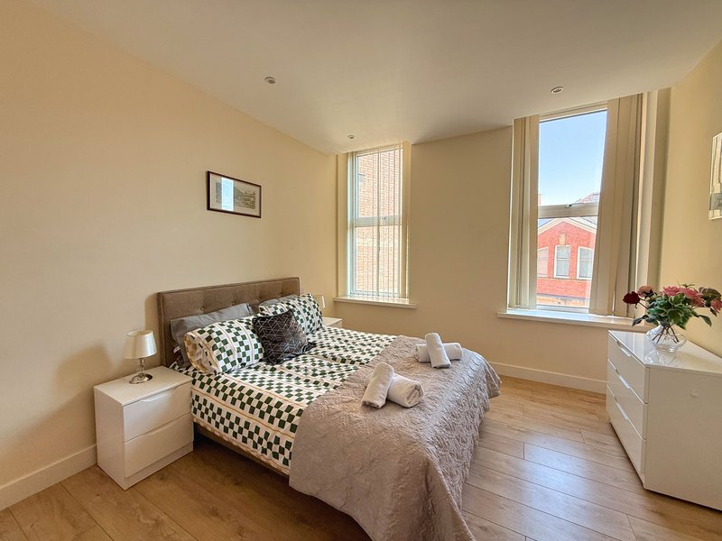 Bright bedroom with double bed, wooden floor, two windows with views, and white furniture
