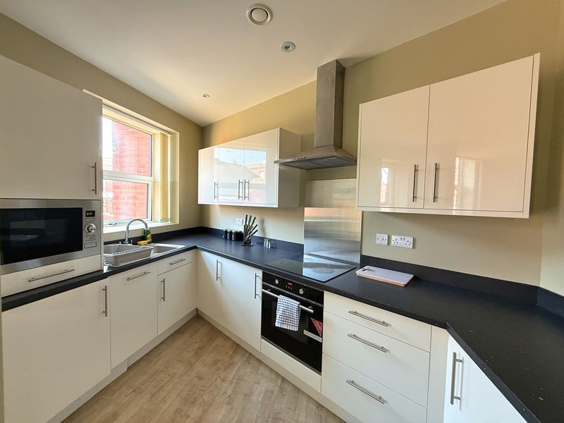 Modern kitchen with cream cabinets, black countertops, stainless steel appliances and window