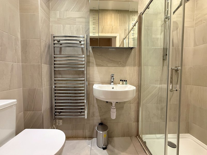 Modern bathroom with toilet, wall-mounted sink, heated towel rail and shower enclosure