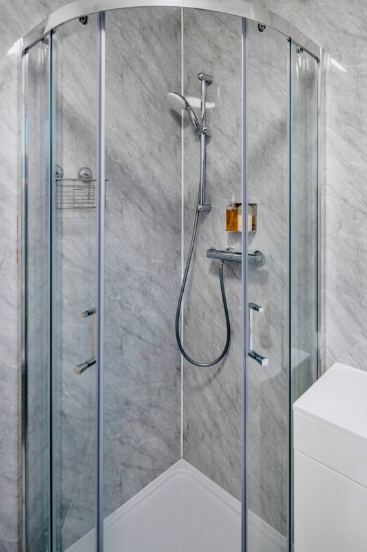 Modern shower enclosure with marble tiles, chrome fixtures and glass panels