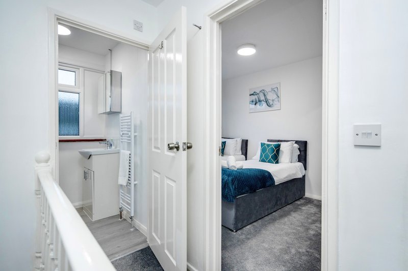 Modern bedroom with double bed, blue bedding and en-suite bathroom visible through doorway