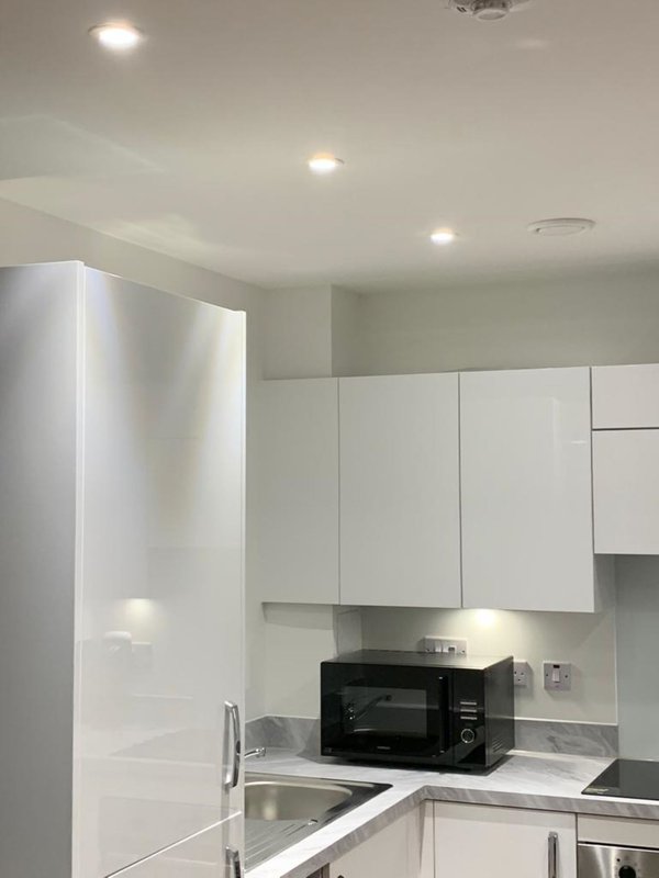 Modern kitchen with white cabinetry, black microwave, and recessed ceiling lights