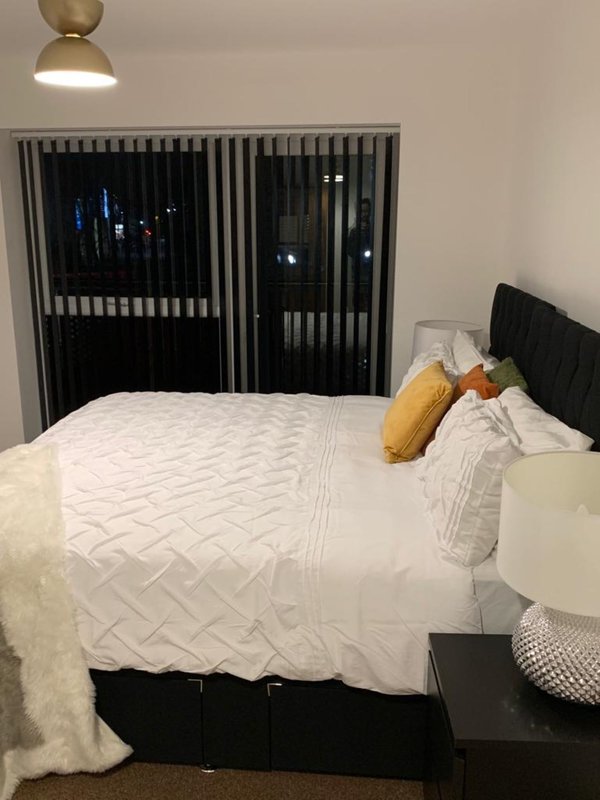 Modern bedroom with white quilted bed, yellow and orange pillows, black headboard and wardrobe