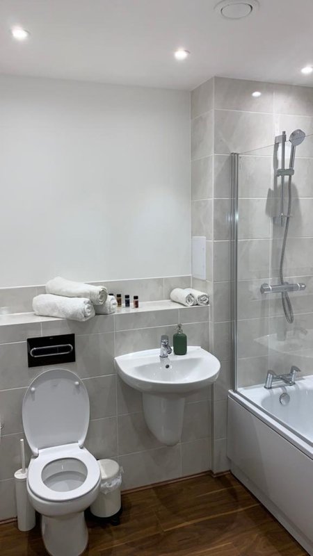 Modern bathroom with toilet, pedestal sink, shower enclosure and tiled walls