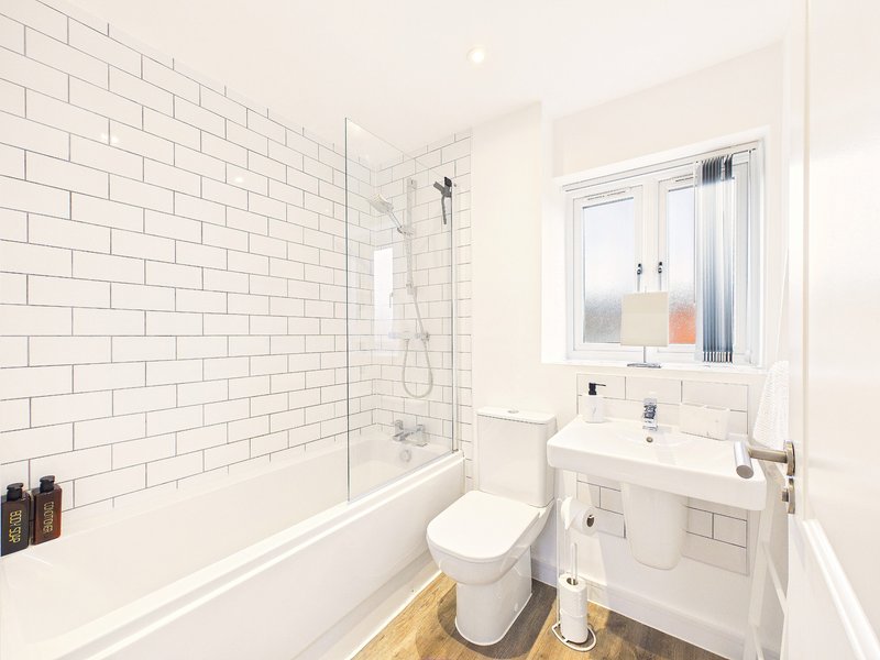 Modern bathroom with white subway tile, bath, toilet, sink and window