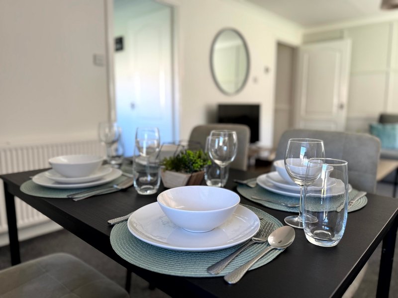 Dining table set for multiple place settings with white plates, glasses and cutlery