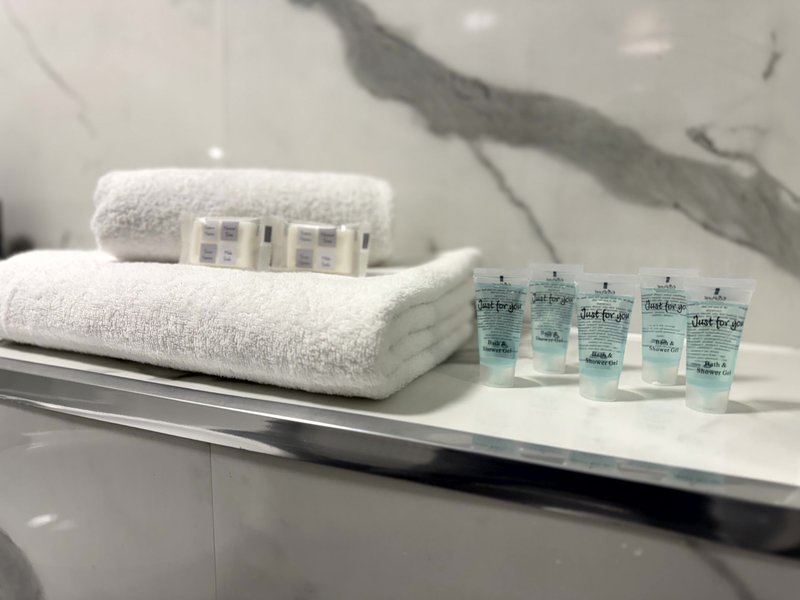 Bathroom counter with folded white towels, toiletries and branded sample bottles