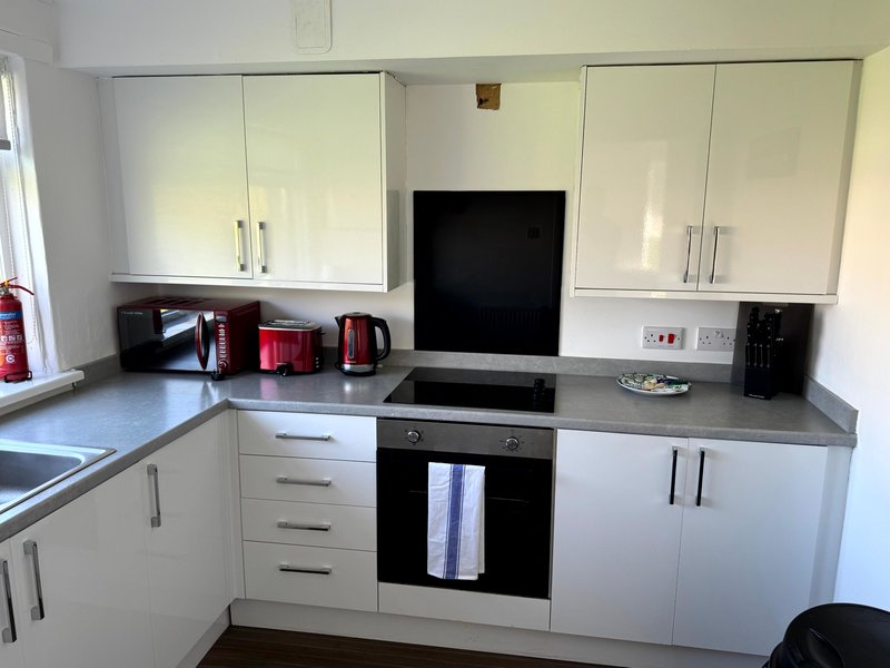 Modern white kitchen with built-in oven, gas hob, grey worktops and stainless steel appliances