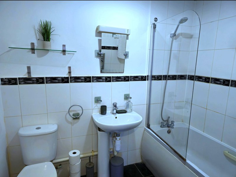 Modern bathroom with toilet, pedestal sink, shower enclosure and white wall tiles