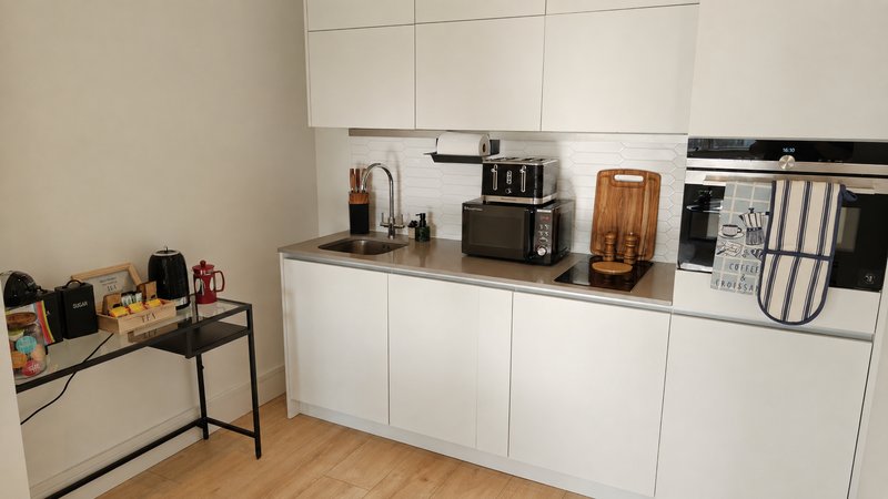 Modern white kitchen with wooden countertop, appliances, and organized counter items