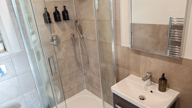 Modern bathroom with walk-in shower, white sink, mirror and towel rail