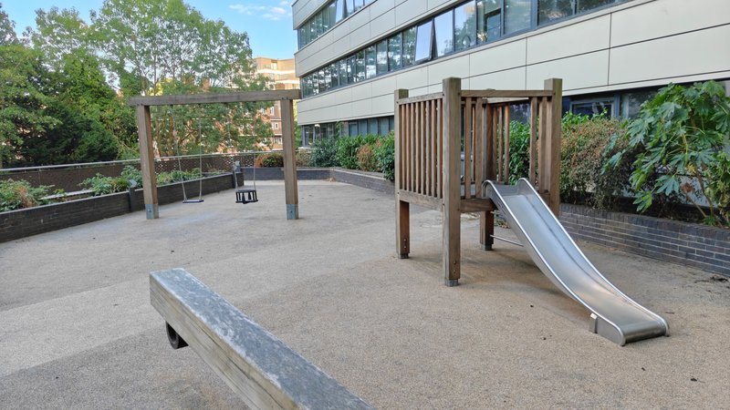 Communal rooftop play area with slide, wooden climbing structure and seating