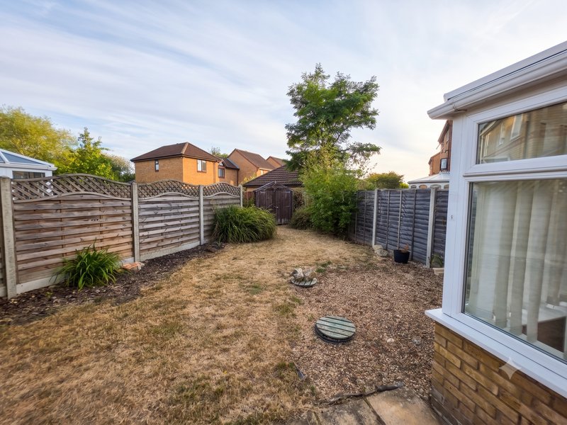 Rear garden with gravel patio, wooden fencing, shrubs and neighboring properties