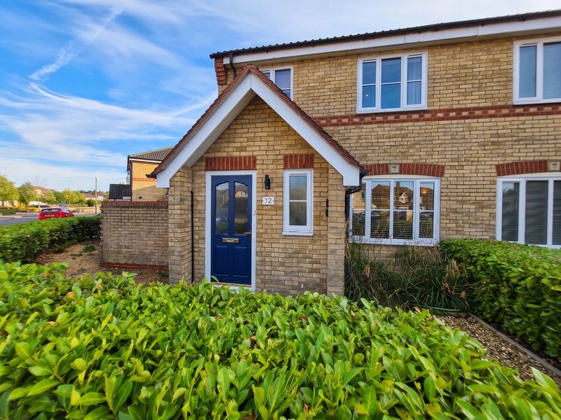 Semi-detached brick house with blue front door, front garden and driveway