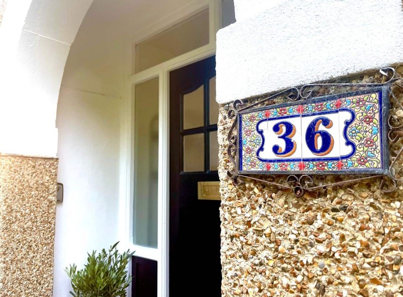 Entrance door with house number 36 plaque and potted plant by door