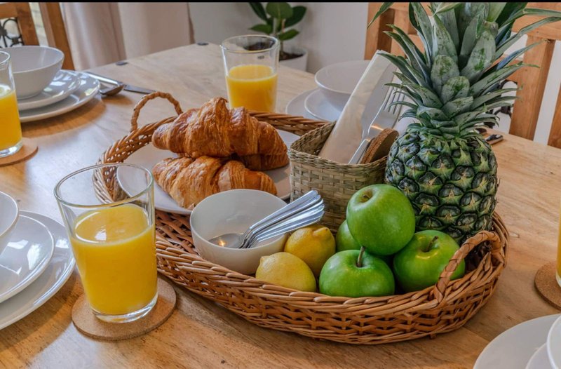 Dining table set with fresh fruit, croissants, orange juice and place settings