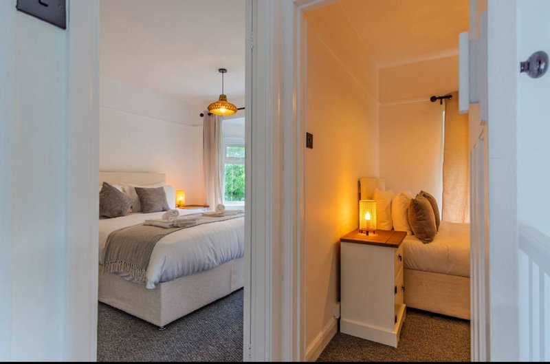 Modern bedroom with double bed, pendant light, and ensuite bathroom visible through open doorway