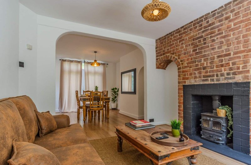 Living room with brown sofa, fireplace, wooden coffee table and archway to dining area