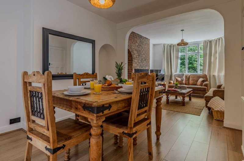 Open-plan dining and living area with wooden table, upholstered seating, and garden views