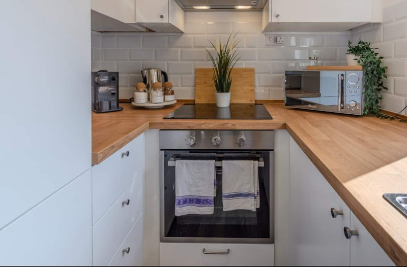 Modern kitchen with white cabinetry, wooden countertops, stainless steel oven and appliances