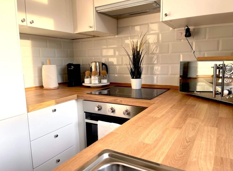 Modern kitchen with white cabinets, wooden countertops, black cooktop and subway tile backsplash