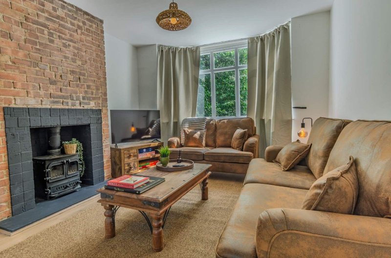 Spacious living room with fireplace, leather seating, wooden coffee table and garden view