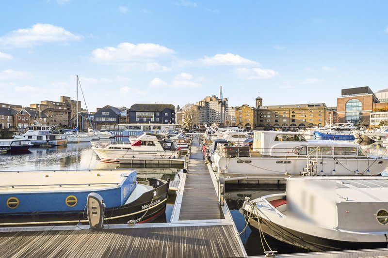 Marina with moored boats, wooden dock, and waterfront residential buildings in background