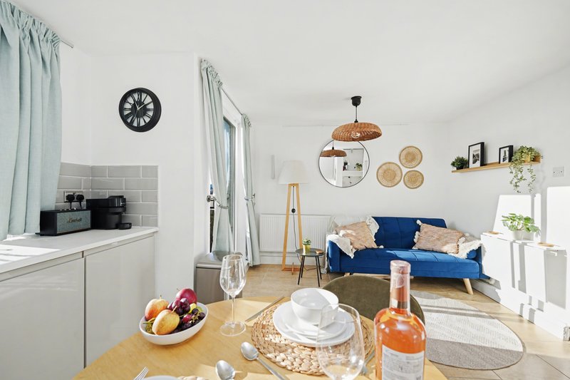 Open-plan living space with dining table, blue sofa, kitchenette and wall decor