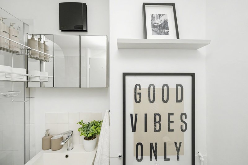 Modern bathroom with white subway tiles, mirror cabinet, shelf, and decorative wall art