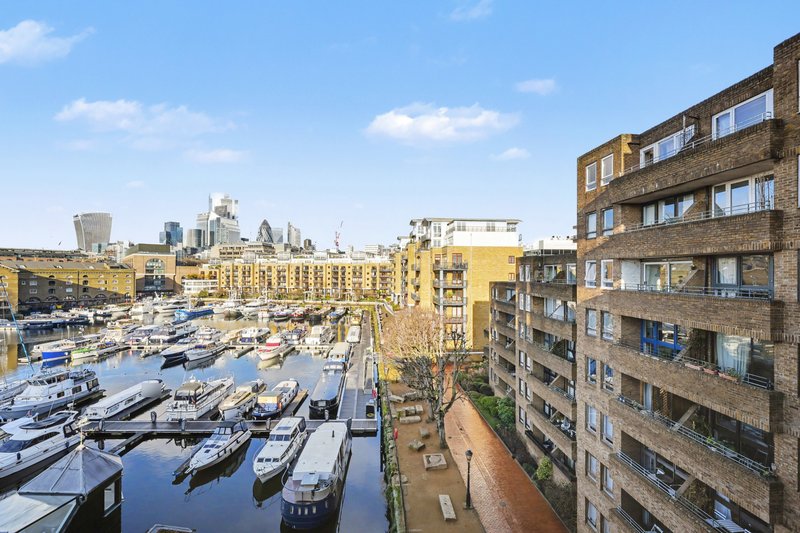 Waterfront view from apartment building overlooking marina with moored boats and city skyline