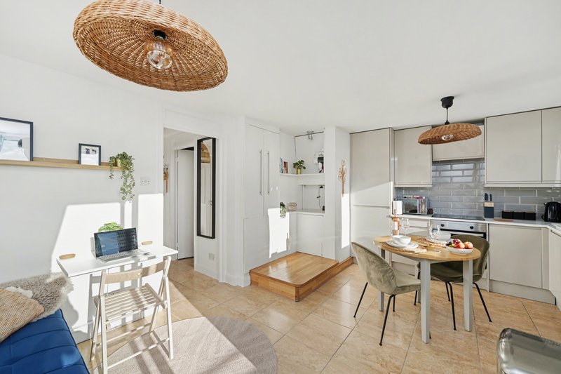 Open-plan kitchen and living area with woven pendant lights, dining table, and modern furnishings