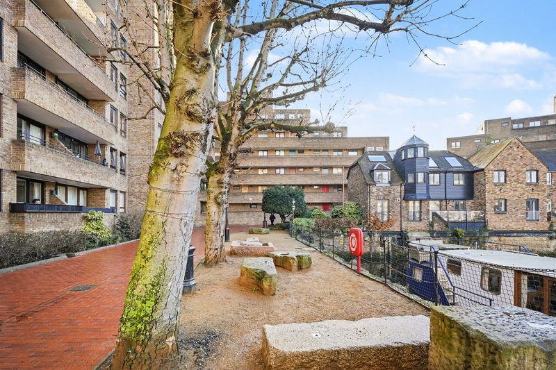 Communal courtyard with brick buildings, bare trees, benches and canal-side setting