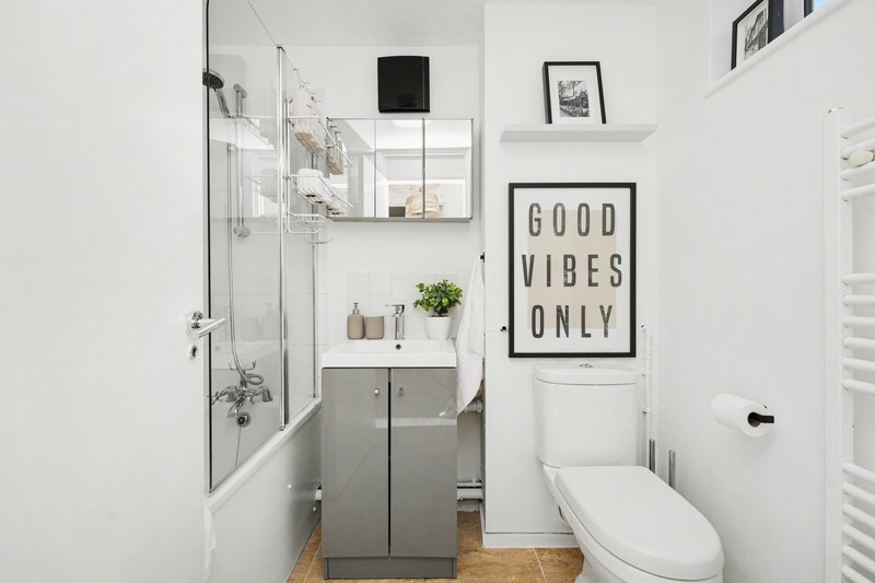 Modern bathroom with shower enclosure, grey vanity, toilet, and decorative wall art